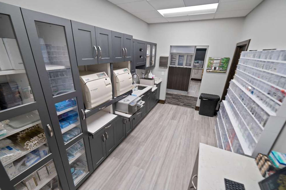 The image depicts an interior view of a well-organized pharmacy with shelves stocked with various products, a countertop displaying items for sale, and a clean, professional appearance.