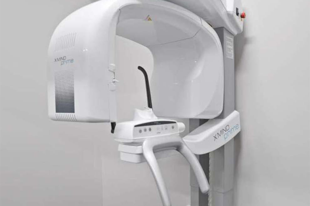 This image shows a modern dental chair with a digital display panel, situated against a plain wall, likely within a dental office setting.