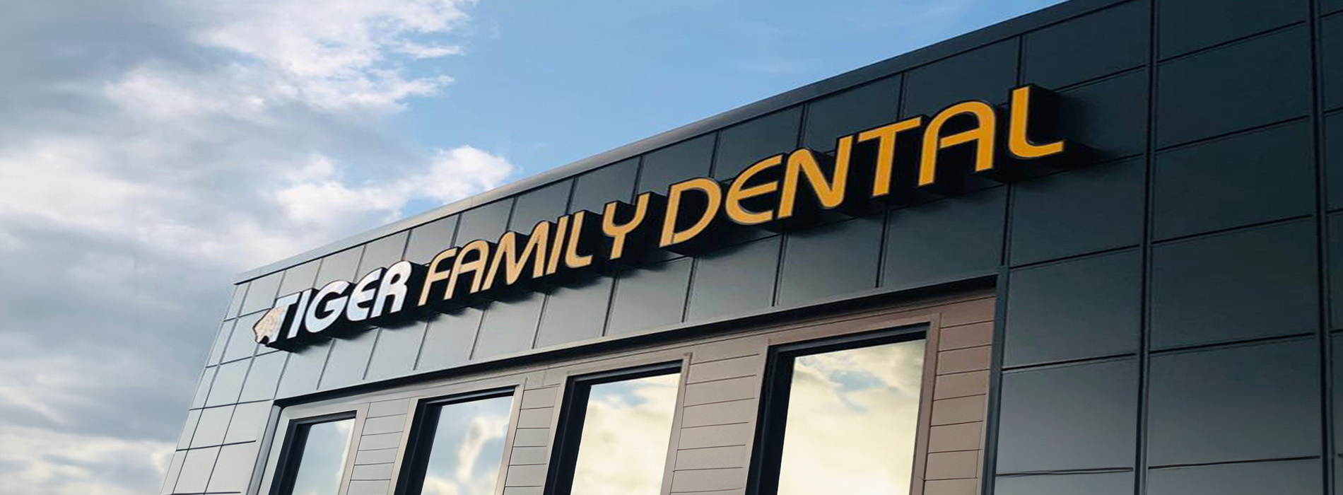 The image shows a building with a sign that reads TIGER FAMILY DENTAL. It appears to be a modern dental practice with a clean, contemporary design.