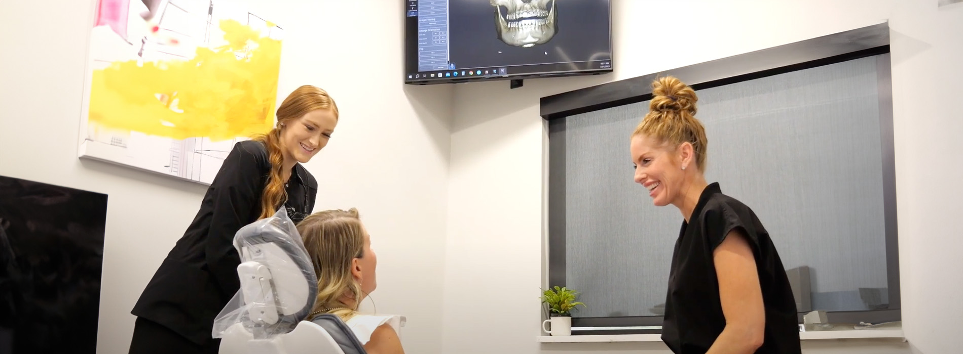 A well-lit reception area with a desk, computer monitor, and potted plant.