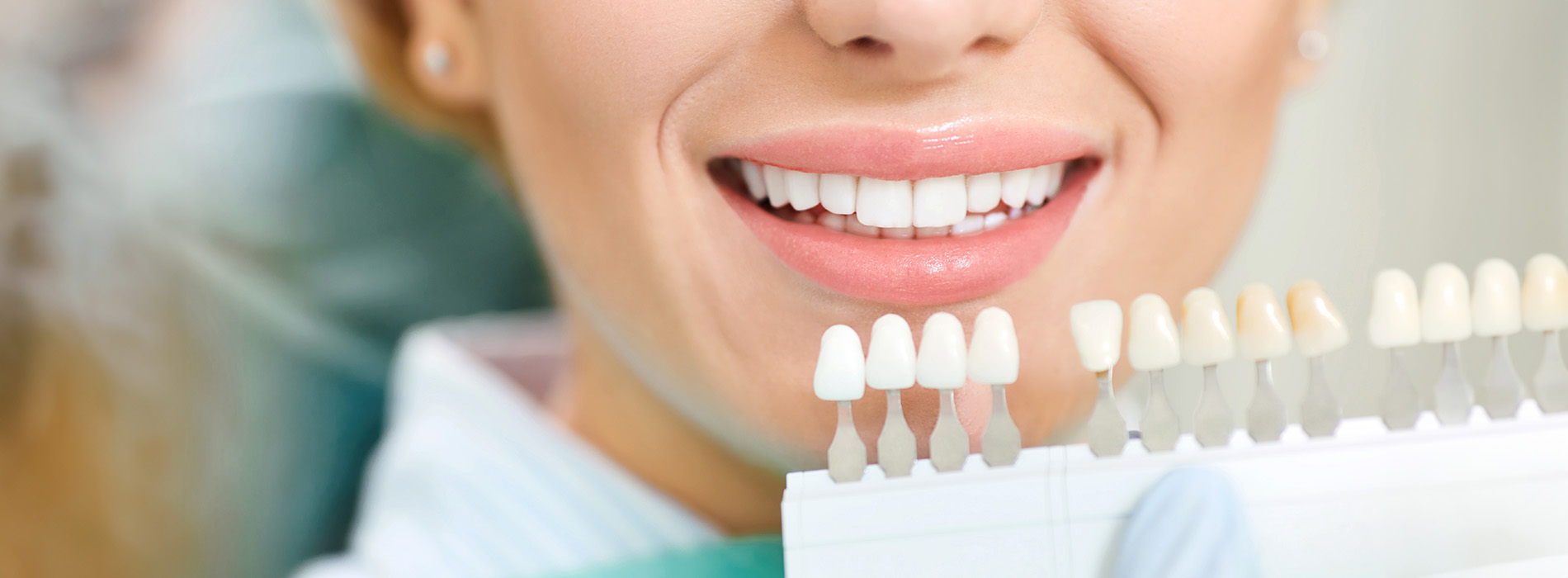 The image shows a person with a broad smile, wearing a white lab coat, holding up their teeth for examination, with a focus on dental hygiene products in the foreground.