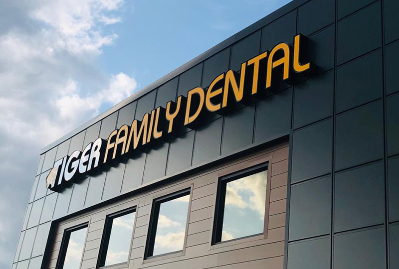 The image shows a building with a sign that reads TIGER FAMILY DENTAL prominently displayed, indicating that this is a dental clinic.