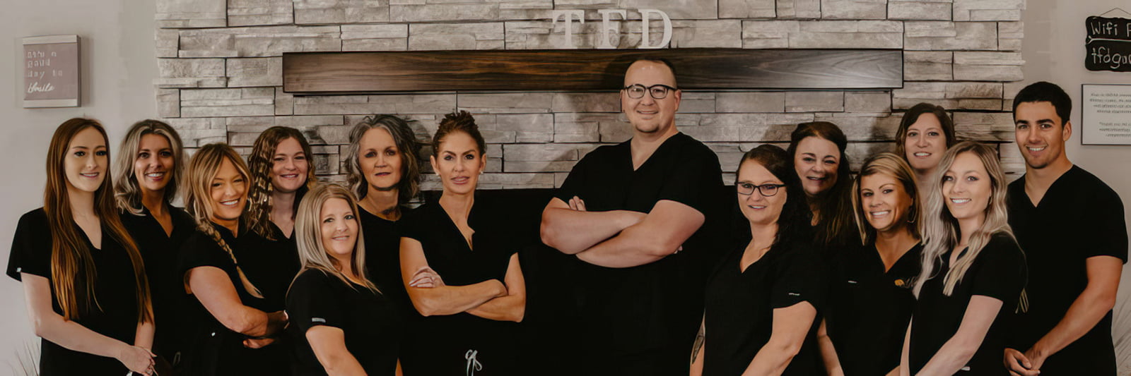 A group of people posing together for a photo, with one person standing behind them.
