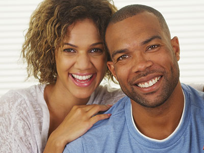 The image depicts a man and a woman posing together with smiles, sharing an intimate moment.