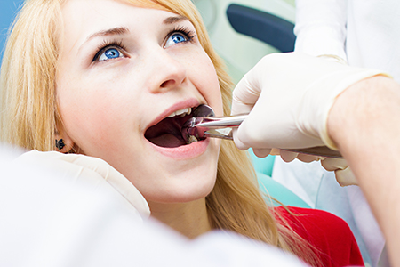 A woman receiving dental care with a dentist performing a procedure on her teeth.