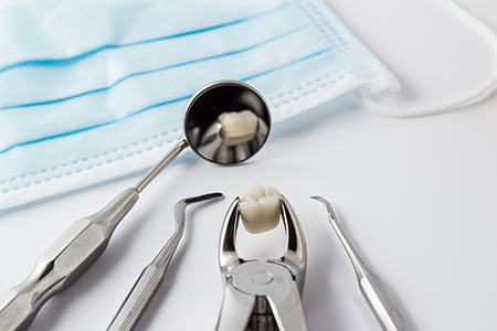 The image shows a dental hygiene setup with multiple dental instruments, including a toothbrush, lying on a table next to a blue surgical drape and a small cup of dental paste.