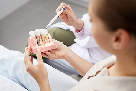 A person holding a pink toothbrush with toothpaste on it, possibly demonstrating oral hygiene practices.