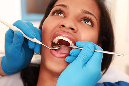 A woman with braces receiving dental care from a professional in a clinical setting.