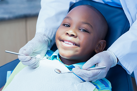 A young boy sitting in a dentist s chair with his mouth open, receiving dental care from a professional.