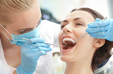 A dental professional performing a dental procedure on a patient s mouth with dental tools and equipment.