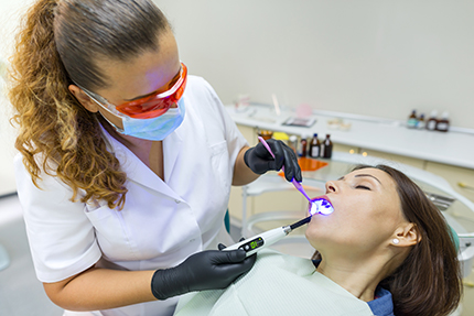 A dental hygienist performing oral care on a patient using a dental drill.